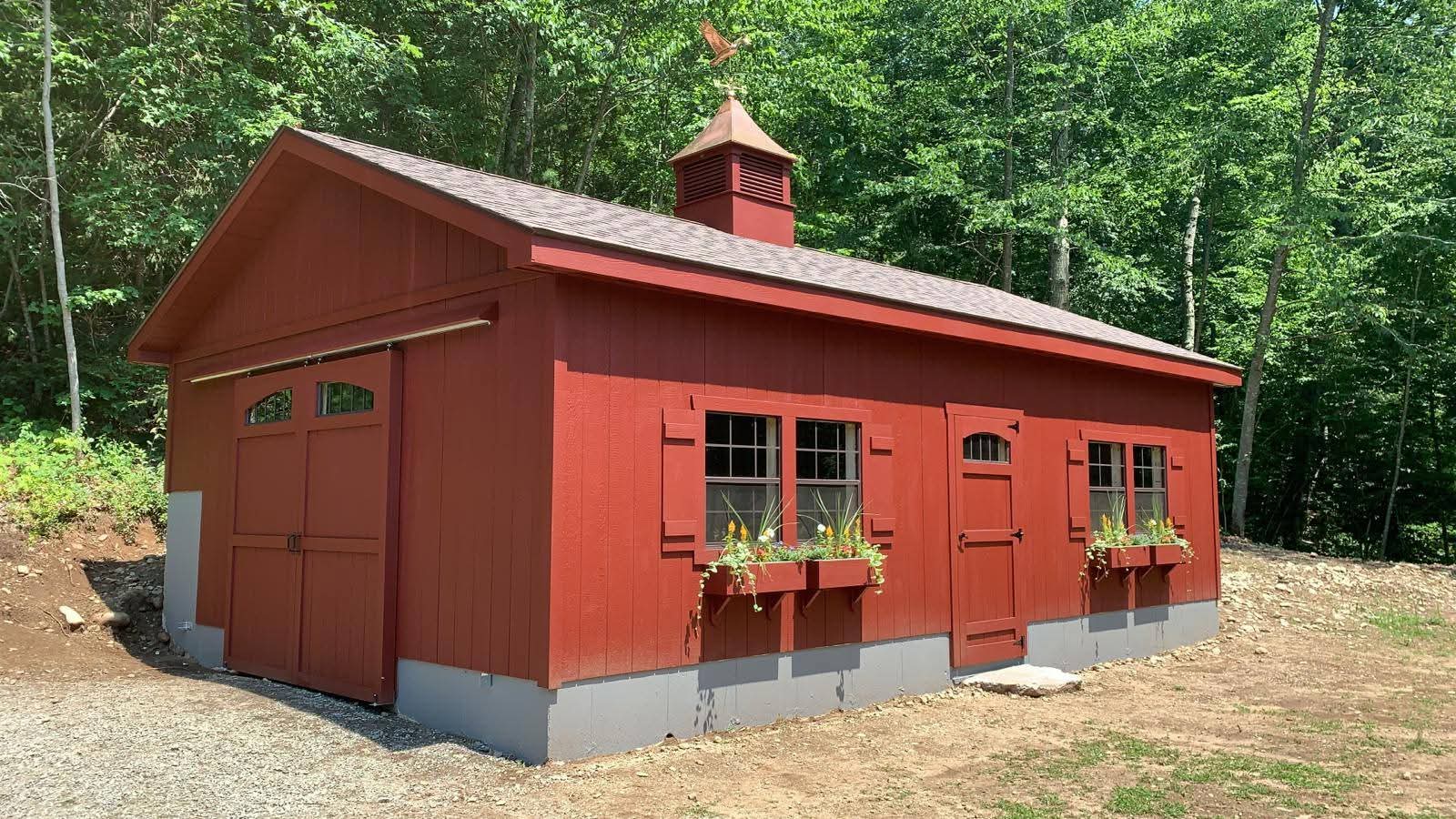 Red barn-style single-level garage, single door on the gable end, cupola and weather vane