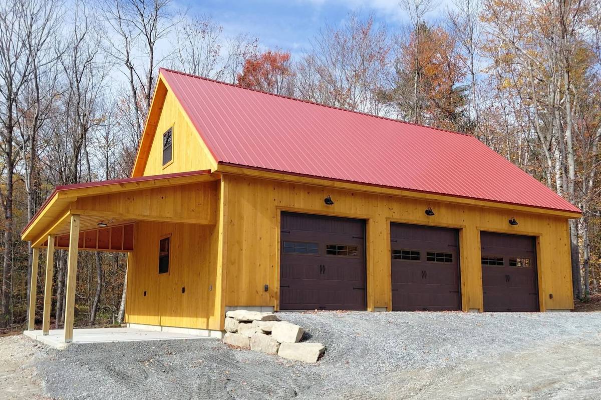 Custom three-door garage with a red metal roof built by Hometown Structures