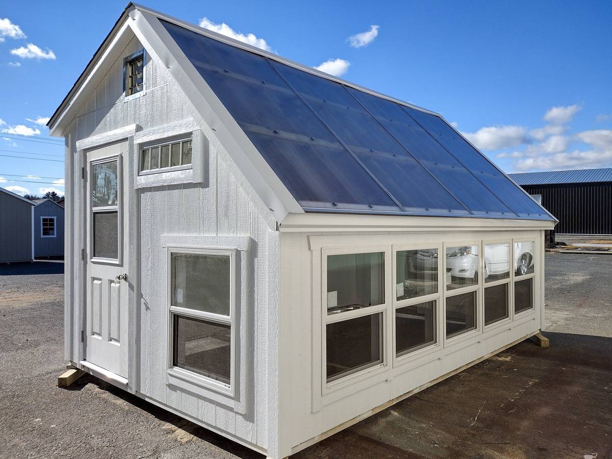 Expanded homestead greenhouse with white siding on a large property
